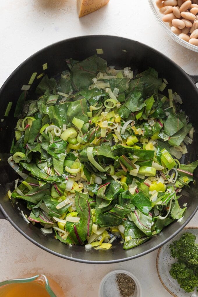 Garlic, red pepper flakes, and Swiss chard added to skillet with leeks and onion.