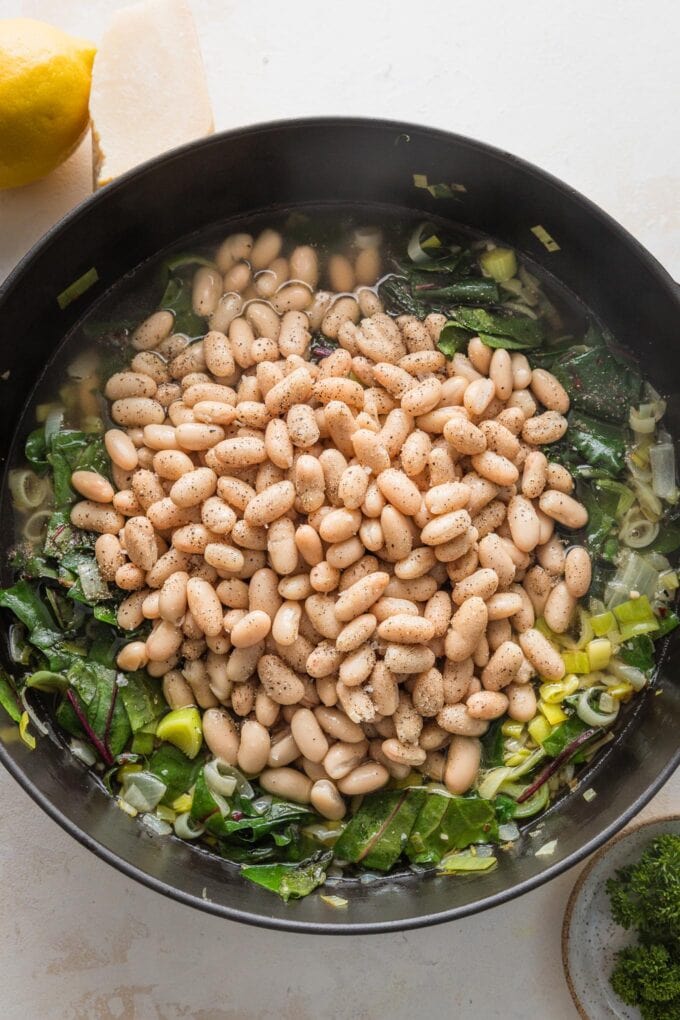 Cannellini beans added to skillet with greens.