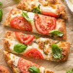 Sliced caprese flatbreads scattered with lots of fresh basil leaves.