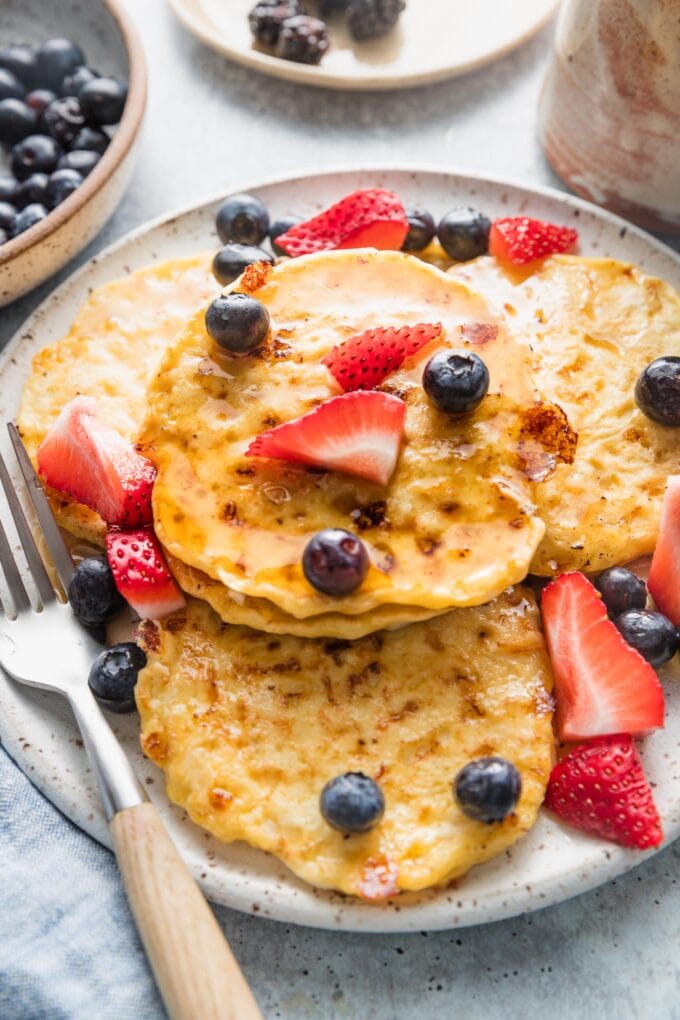 Angled view of a large plate filled with four ingredient cottage cheese pancakes.