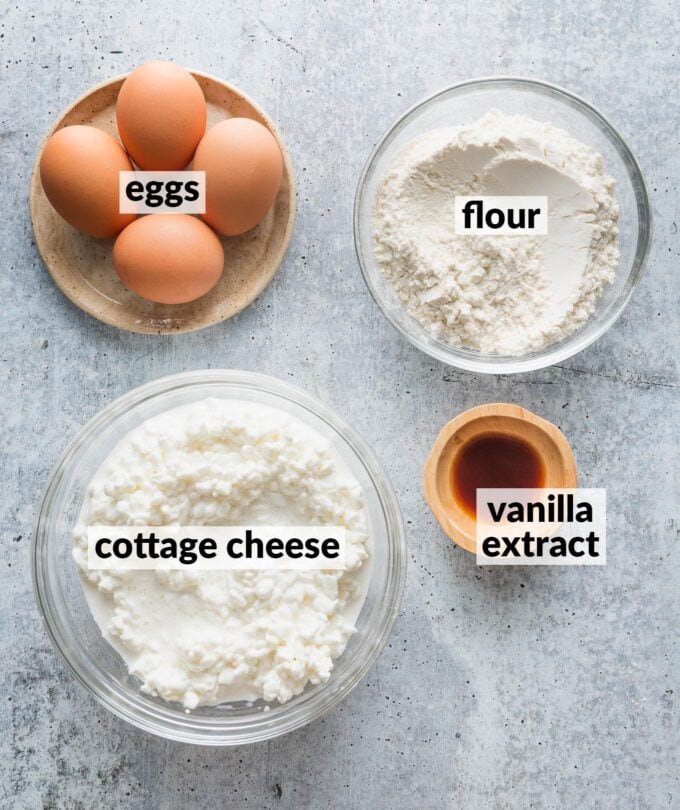 Labeled overhead photo of eggs, cottage cheese, flour, and vanilla extract, measured and ready to whisk into pancakes.
