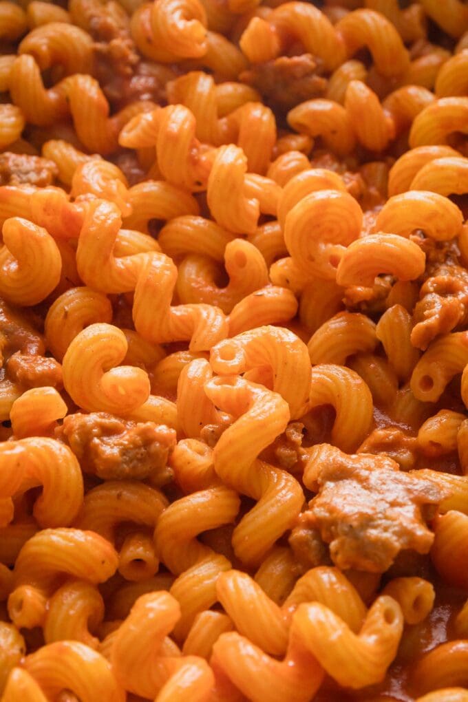 Close up of cavatappi coated in a creamy tomato sauce and mixed with crumbled Italian sausage.