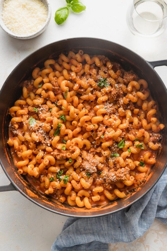 Large cast iron skillet full of creamy tomato sausage pasta.