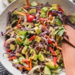 Large white ceramic bowl full of an easy Mexican salad with avocado, cabbage, peppers, tortilla strips, and a red wine vinaigrette.