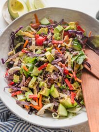 Large white ceramic bowl full of an easy Mexican salad with avocado, cabbage, peppers, tortilla strips, and a red wine vinaigrette.