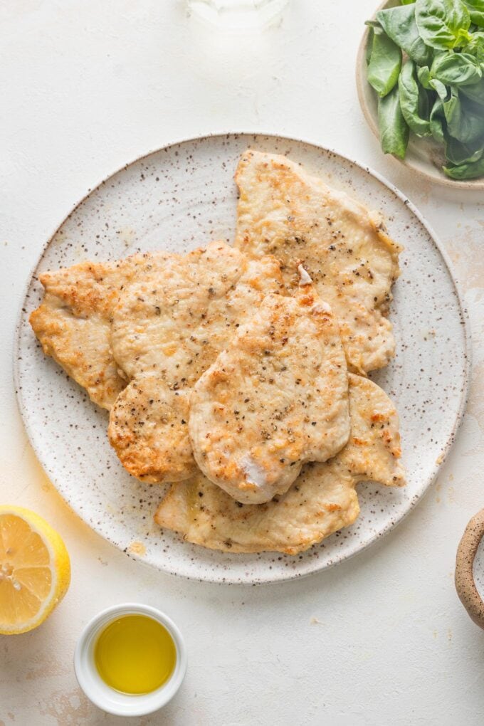 Browned chicken cutlets resting on a large white plate.