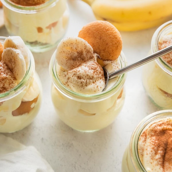 Small tulip-shaped glass jars with individual portions of banana pudding.