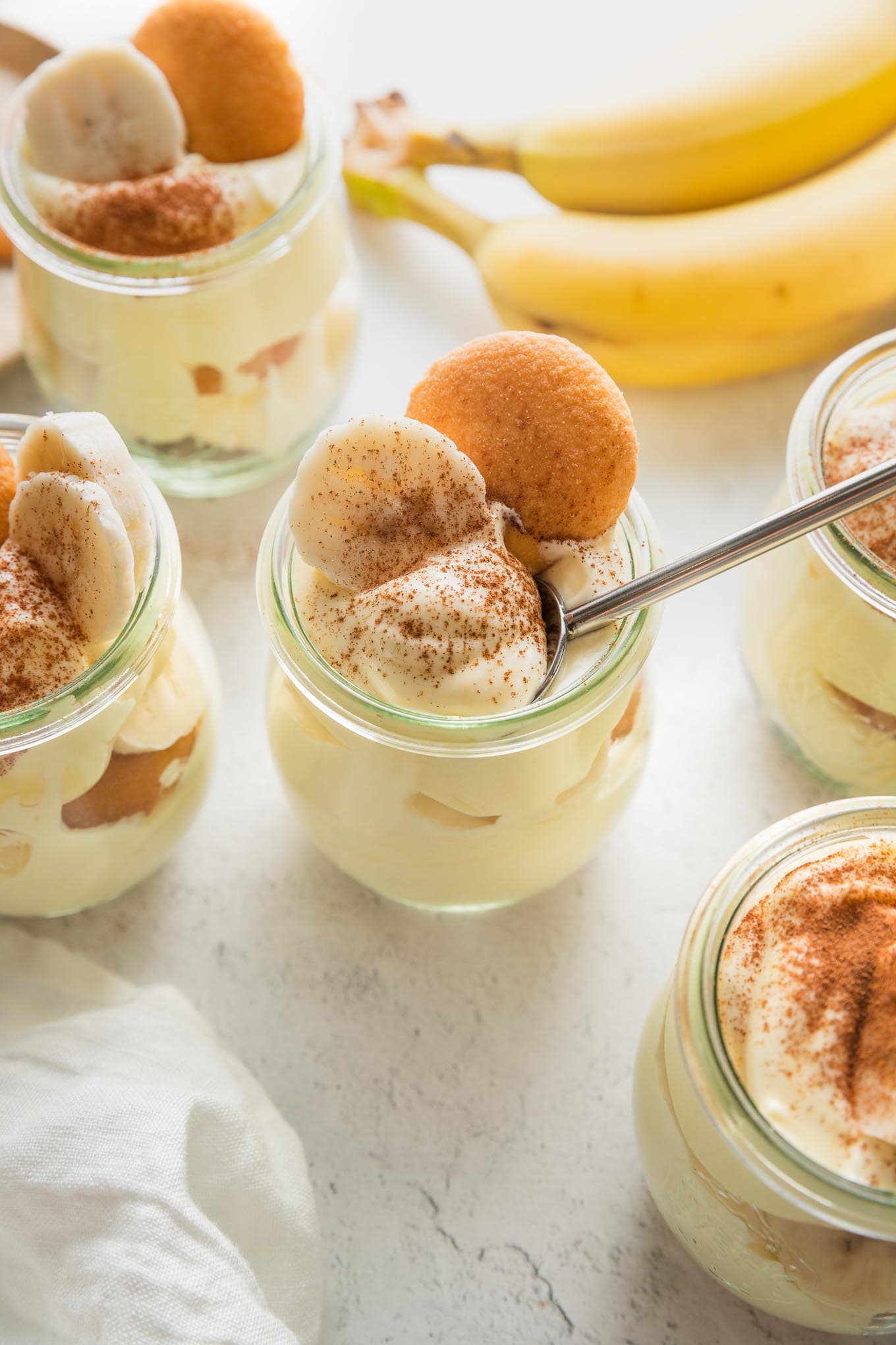 Small tulip-shaped glass jars with individual portions of banana pudding.