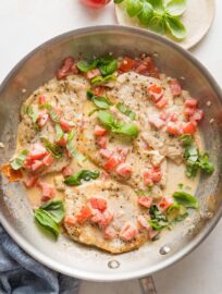 Overhead view of a skillet full of creamy tomato basil chicken.