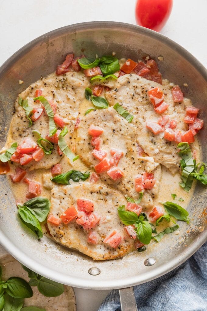 Overhead view of a skillet full of creamy tomato basil chicken.
