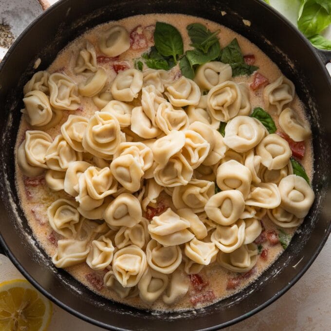Tortellini piled into cast iron skillet on top of sauce.