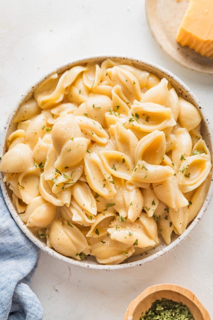 Bowl full of creamy Instant Pot mac and cheese made with small shells and garnished with dried parsley.
