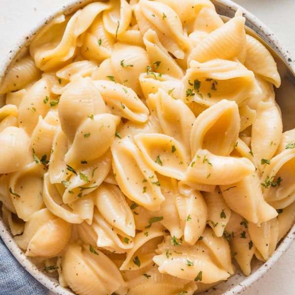 Close up of a spoon scooping out a portion of Instant Pot mac and cheese from a small serving bowl.