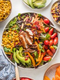 Bowl full of Santa Fe chicken salad with avocado, black beans, tomato, and corn.