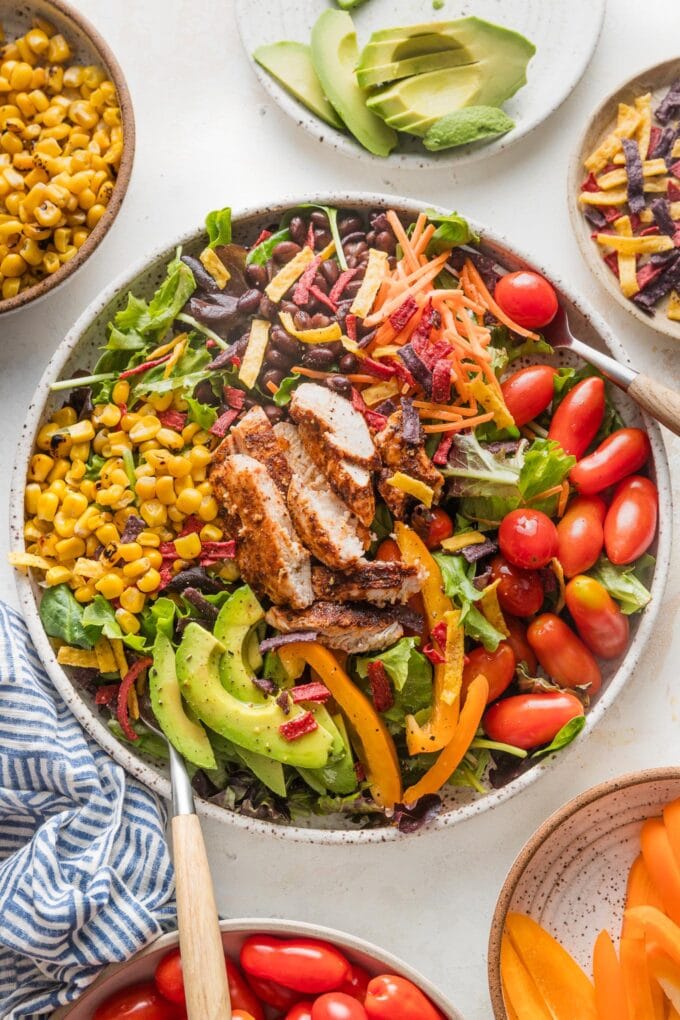 Bowl full of Santa Fe chicken salad with avocado, black beans, tomato, and corn.