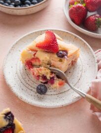 Close up of a fork slicing off a small bite of cake with fresh berries.