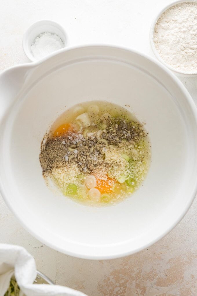 Eggs, Parmesan, green onions, and seasonings ready to whisk together in a large mixing bowl.