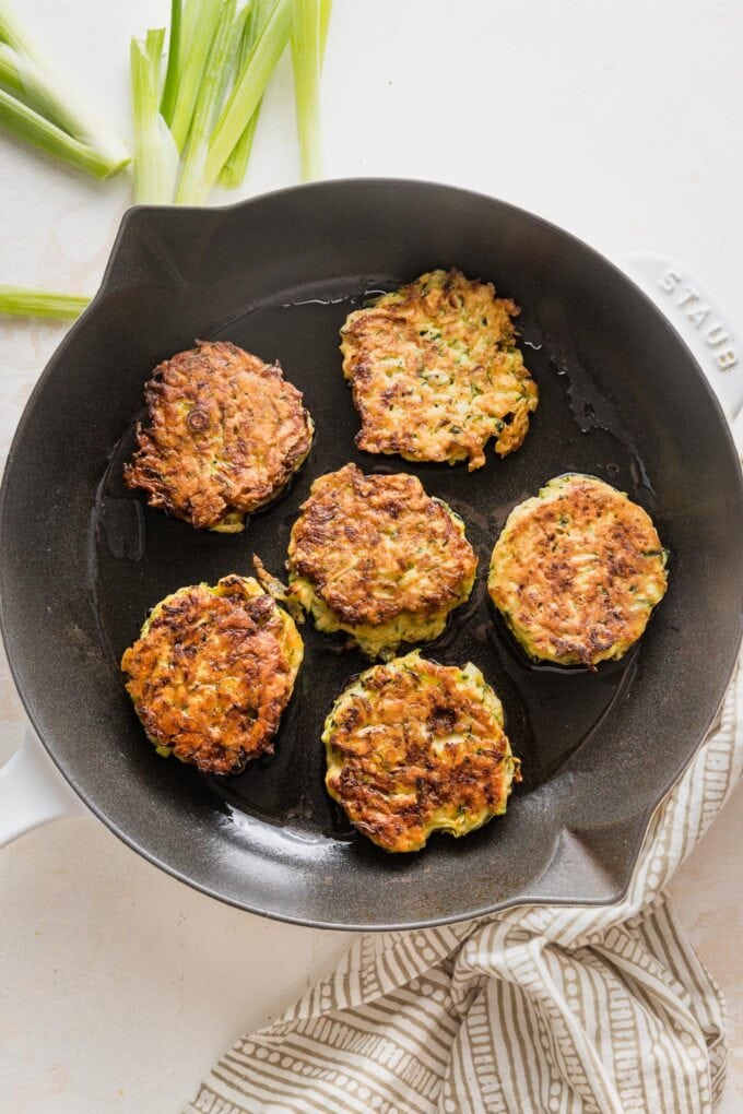 Small cast iron skillet with just-cooked zucchini fritters inside.