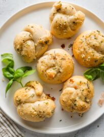 A handful of biscuit garlic knots arranged on a small plate.