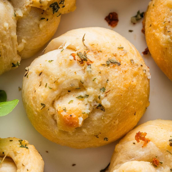 Close up of a butter Parmesan brushed garlic knot made out of biscuit dough.