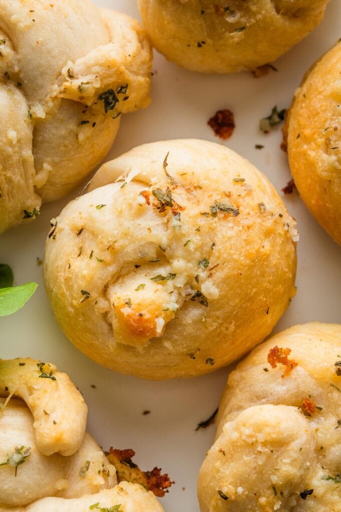 Close up of a butter Parmesan brushed garlic knot made out of biscuit dough.