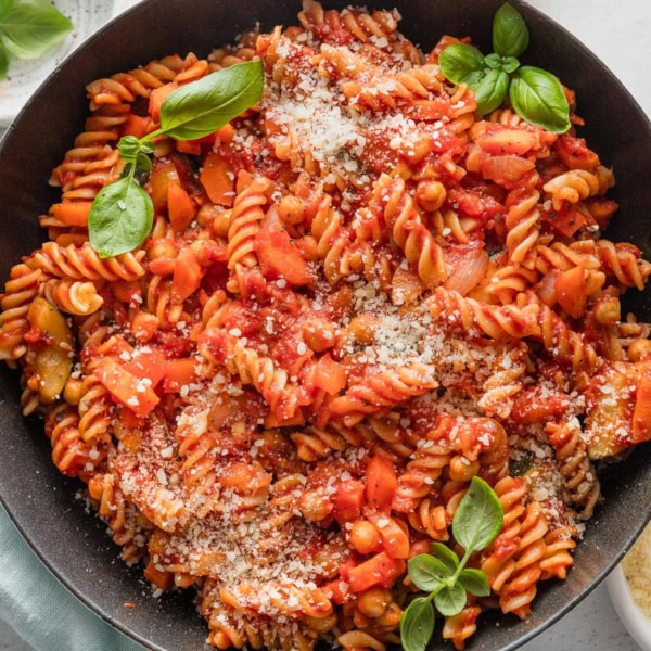Skillet full of veggie pasta marinara with zucchini, carrot, onion, and bell pepper.