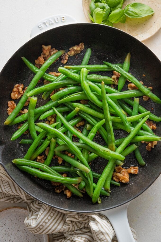 Blanched green beans added to a skillet with walnuts toasted in butter and red pepper flakes.