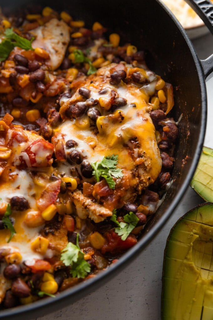 Close up of a cheesy Santa Fe chicken breast in a skillet.