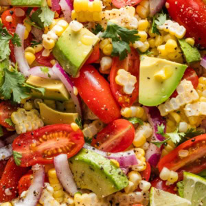 Close up of a corn tomato avocado salad with red onion and cilantro.