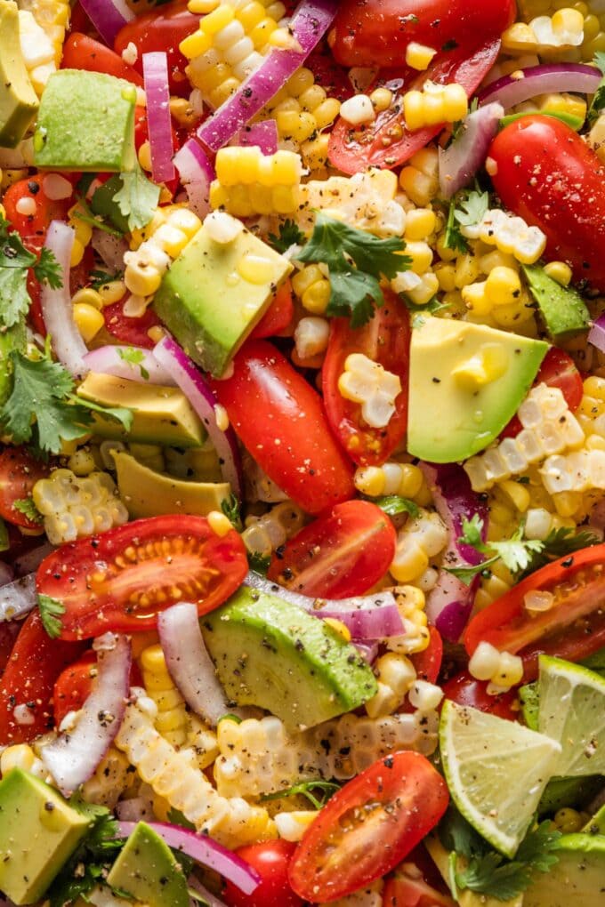 Close up of a corn tomato avocado salad with red onion and cilantro.