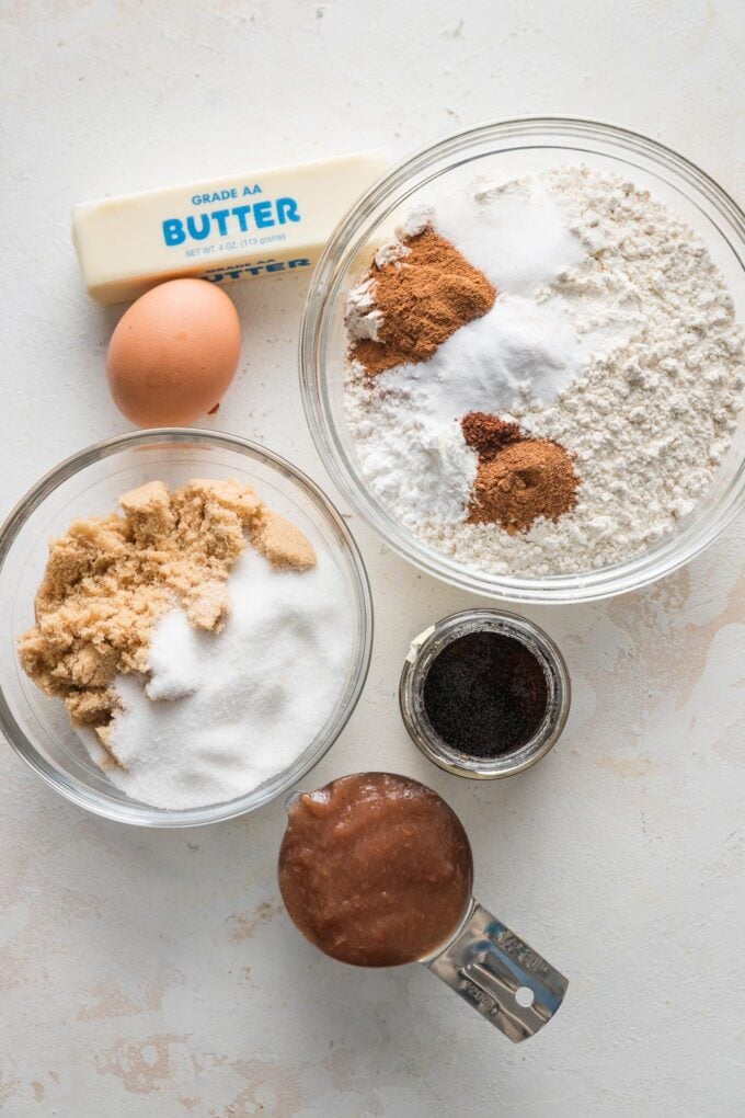 Overhead photo of butter, brown sugar, granulated sugar, vanilla bean paste, apple butter, an egg, flour, cream of tartar, baking soda, baking powder, and spices, all in prep bowls and ready to bake.
