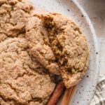 Close up of apple butter snickerdoodle cookies, with one broken in half to show the tender, chewy interior.