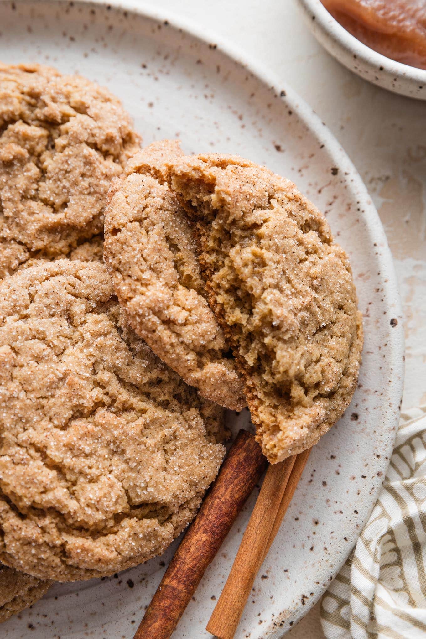 Close up of apple butter snickerdoodle cookies, with one broken in half to show the tender, chewy interior.
