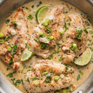 Creamy cilantro lime chicken skillet garnished with green onions, lime slices, and served with rice.