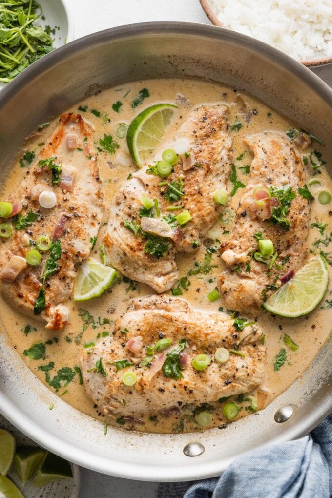 Creamy cilantro lime chicken skillet garnished with green onions, lime slices, and served with rice.