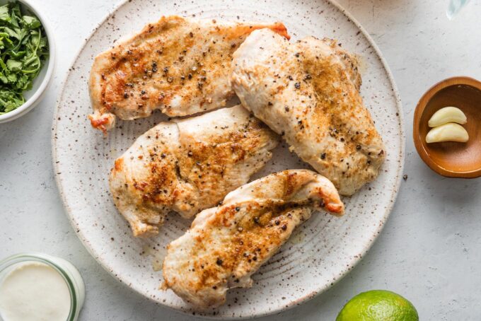 Seared chicken breasts removed to a plate to rest.