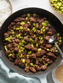 Cast iron skillet full of ground beef with edamame.