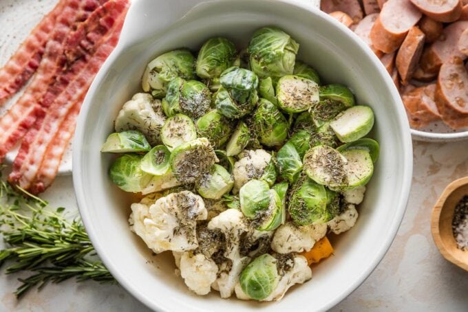 Harvest veggies tossed together in a bowl with olive oil and seasonings.