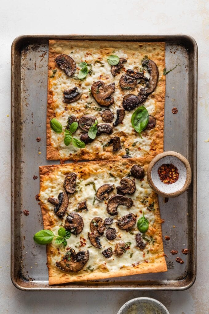 Large baking sheet with crisp mushroom flatbreads, just removed from the oven.