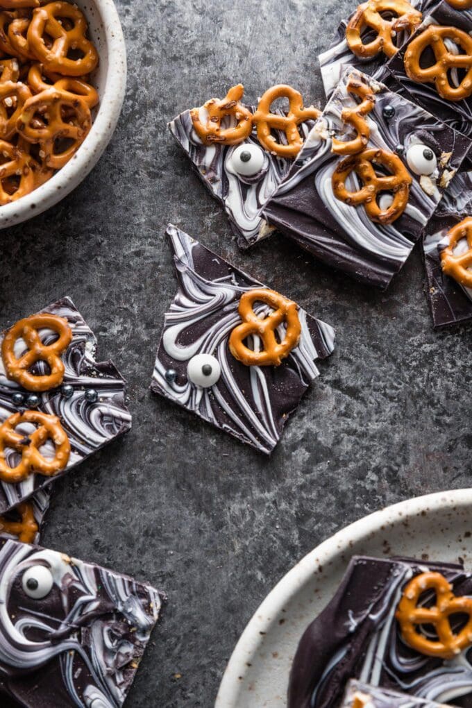 Dark black countertop scattered with chocolate and white chocolate swirled bark with pretzels pressed into the top.