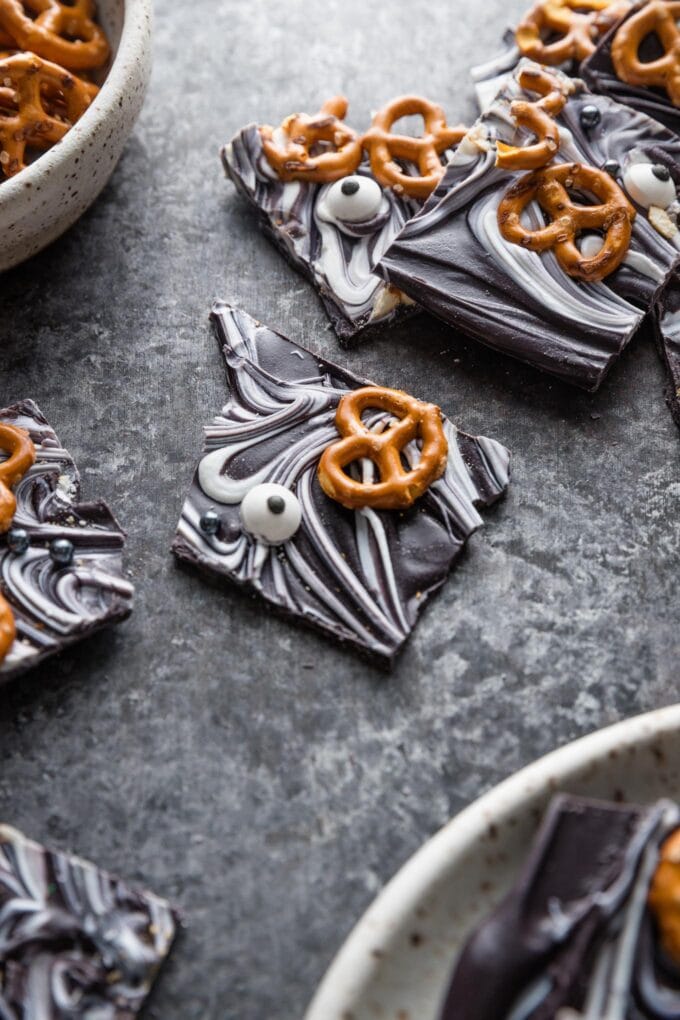 Angled view of dark swirled "boo bark" pressed with miniature pretzels and candy eyes.