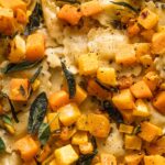 Close up view of cheese ravioli with brown butter sauce, sage, lemon juice, and cubed butternut squash.