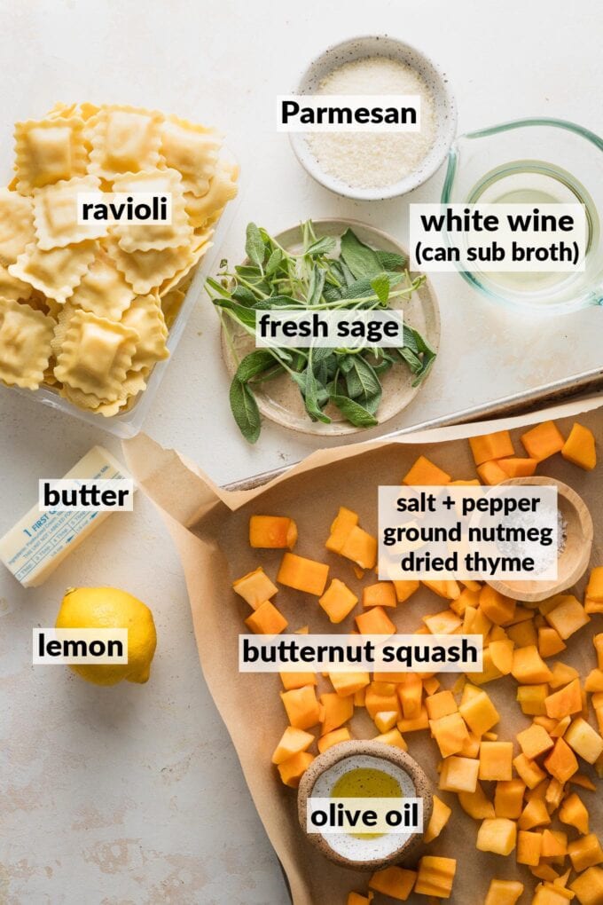 Labeled overhead photo of cubed butternut squash on a sheet pan, seasonings, olive oil, fresh sage leaves, cheese ravioli, white wine, a fresh lemon, butter, and Parmesan cheese.