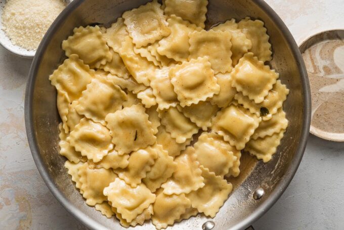 Ravioli added to a skillet with browned butter.