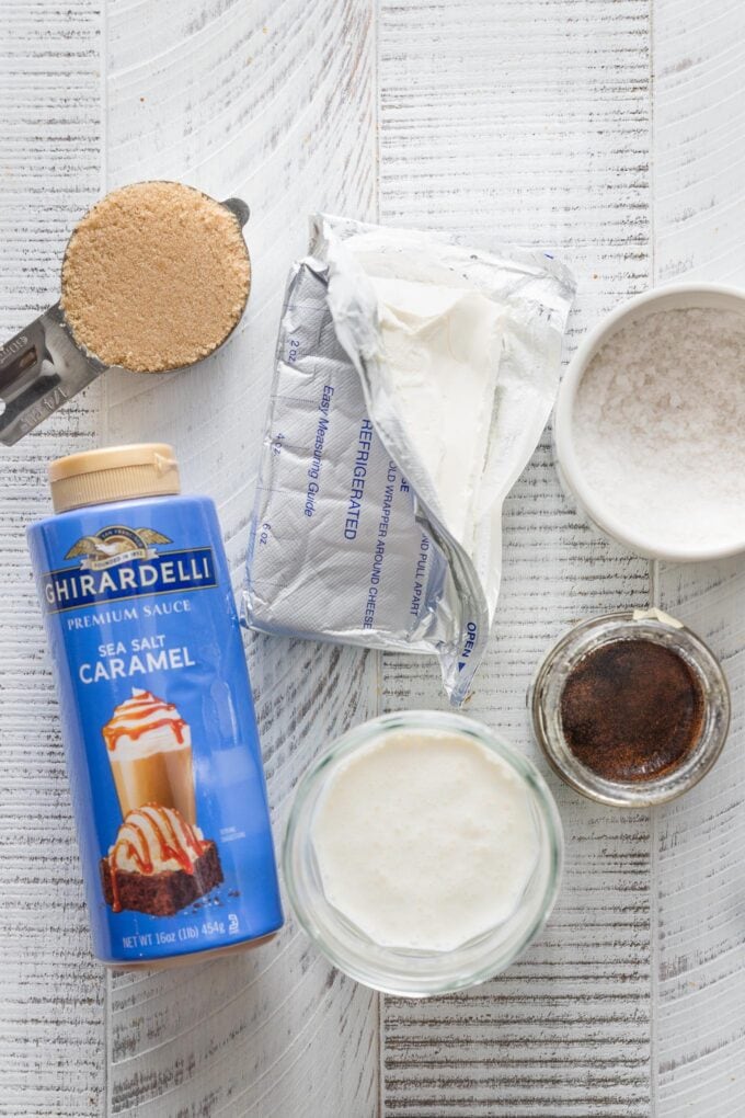 Overhead view of cream cheese, caramel sauce, brown sugar, sea salt, and heavy cream.