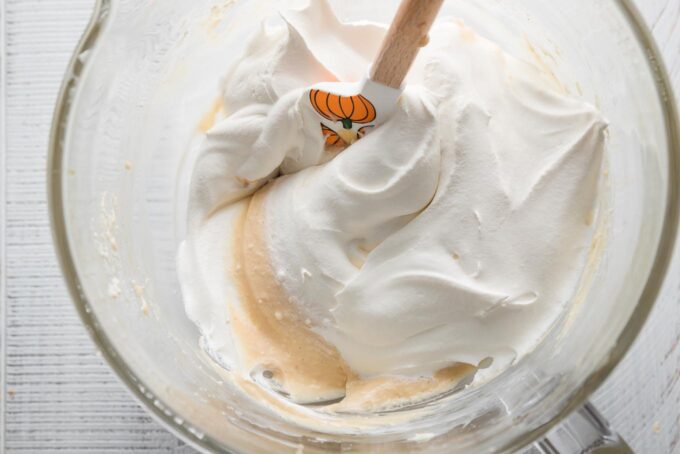 Whipped cream being folded into a caramel cheesecake dip mixture.