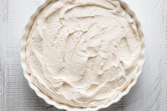 Caramel apple cheesecake dip mixture scraped out into a low fluted tart pan.