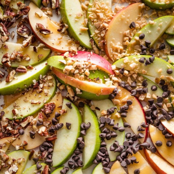 Close up of caramel apple slices topped with toffee bits, pecans, and chocolate chips.