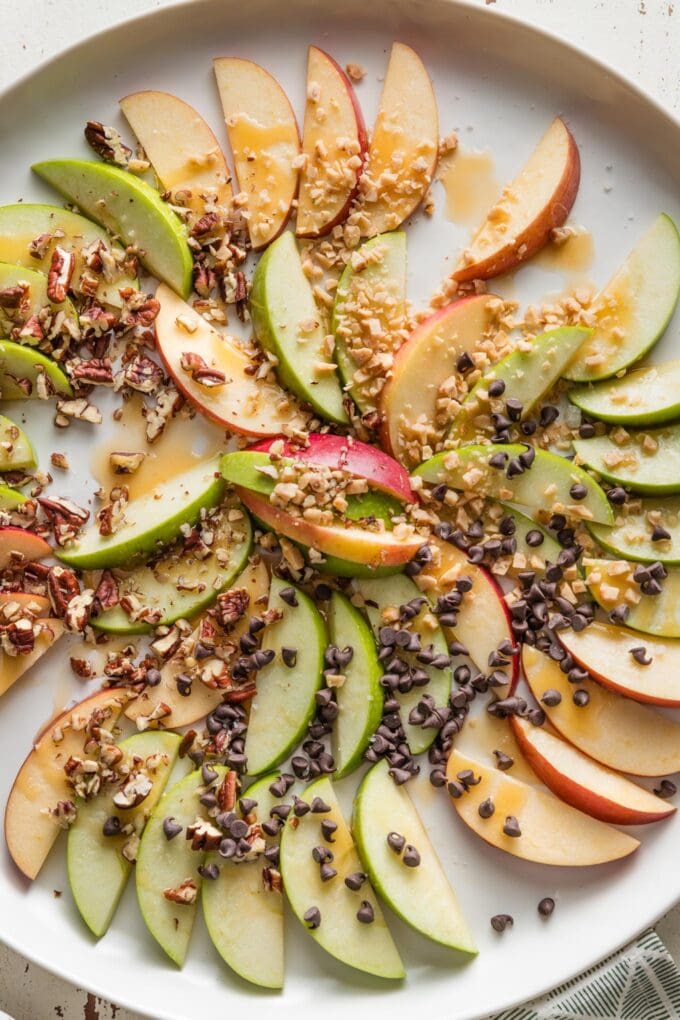 White serving platter with several helpings of caramel apple slices removed from it.