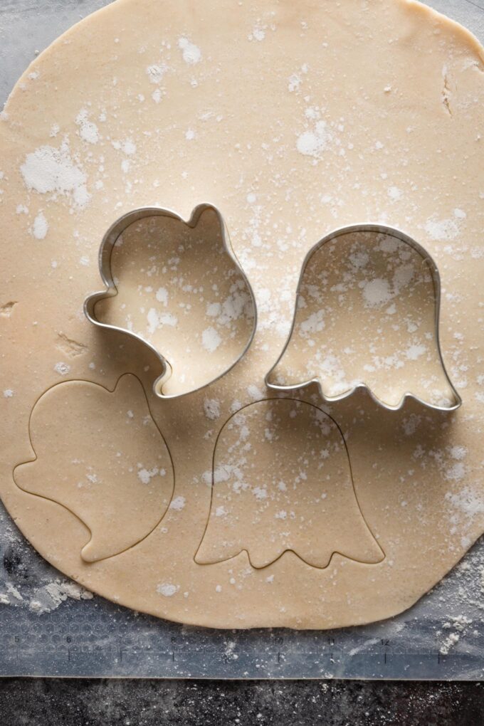 Ghost cookie cutters cutting shapes out of rolled out pie crust.
